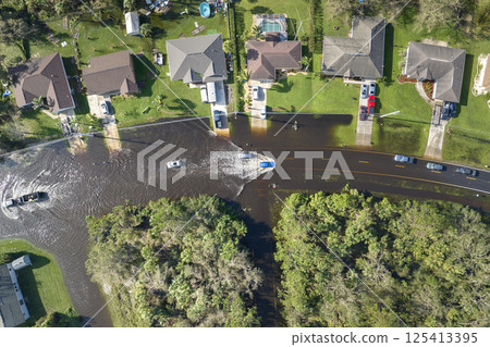 Flooded Florida road with evacuating cars and surrounded with water houses in suburban residential area. Consequences of hurricane natural disaster 125413395