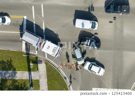 First responders responding to car accident site on American street. Emergency services helping victims of vehicle crash on road in USA 125413400