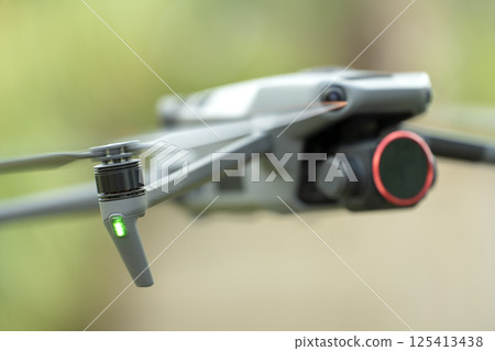 Drone with digital camera and fast rotating propellers flying taking video and pictures Drone with digital camera and fast rotating propellers flying taking video and pictures 125413438