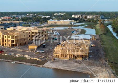 Development of residential housing in American suburbs. Unfinished frames of apartment condos with wooden roof beams under construction. Real estate market in the USA 125413451