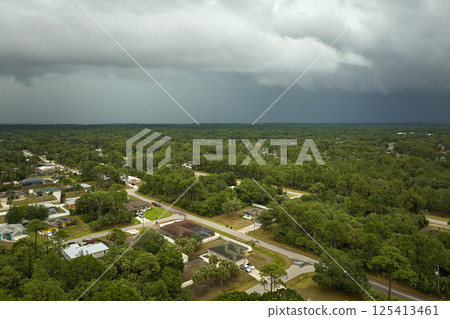 Dark stormy clouds forming on gloomy sky before heavy rainfall over suburban town area 125413461