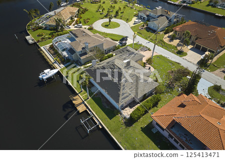 Damaged house roof with missing shingles after hurricane Ian in Florida. Consequences of natural disaster 125413471