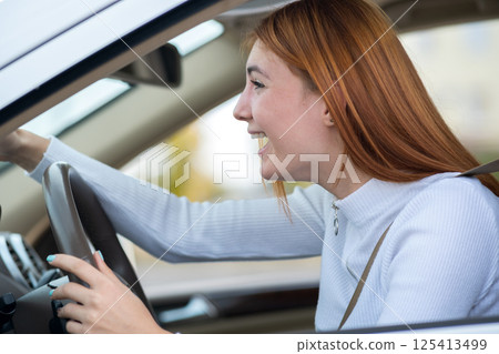 Closeup portrait of pissed off displeased angry aggressive woman driving a car shouting at someone with hand fist up. Negative human expression consept. 125413499