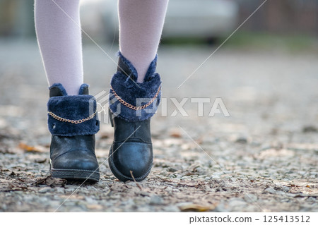 Closeup of child girl feet in pink leggings and fashionable autumn shoes standing outdoors in sunny fall weather. 125413512