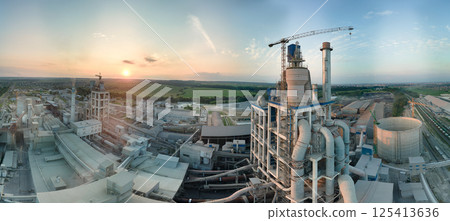 Cement plant with high factory structure and tower cranes at industrial production area. Manufacture, global industry and air pollution concept Cement plant with high factory structure and tower cranes at industrial production area. Manufacture, global industry and air pollution concept 125413636