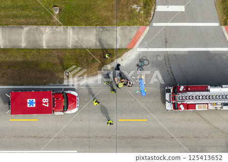 Car crash with first responders helping cyclist on a stretcher who was hit by car at accident site on American street. Vehicle and pedestrian collision on road in USA 125413652