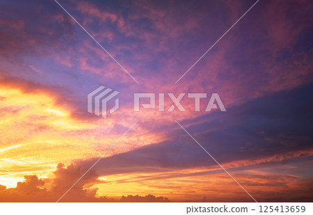 Bright sunset with setting sun behind vivid orange and yellow clouds 125413659