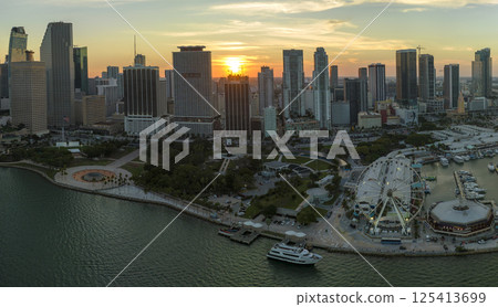 American urban landscape at sunset. Skyviews Miami Observation Wheel at Bayside Marketplace with reflections in Biscayne Bay water and high illuminated skyscrapers of Brickell, city's financial center 125413699