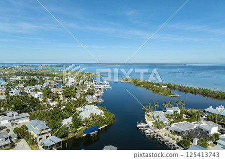 Aerial view of wealthy waterfront neighborhood. Expensive mansions between green palm trees on Gulf of Mexico shore in island small town Boca Grande on Gasparilla Island in southwest Florida, USA Aerial view of wealthy waterfront neighborhood. Expensive mansions between green palm trees on Gulf of Mexico shore in island small town Boca Grande on Gasparilla Island in southwest Florida, USA 125413743