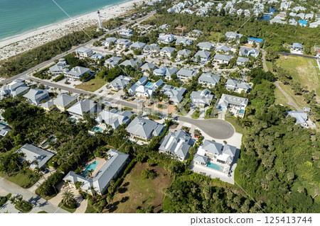 Aerial view of wealthy waterfront neighborhood. Expensive mansions between green palm trees on Gulf of Mexico shore in island small town Boca Grande on Gasparilla Island in southwest Florida, USA Aerial view of wealthy waterfront neighborhood. Expensive mansions between green palm trees on Gulf of Mexico shore in island small town Boca Grande on Gasparilla Island in southwest Florida, USA 125413744