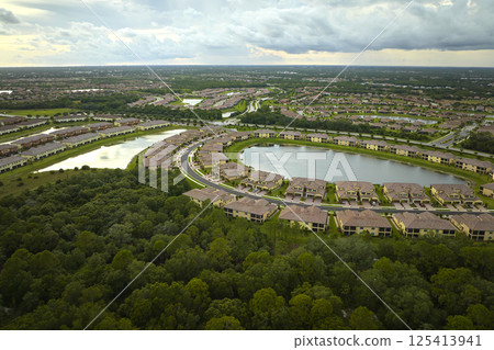 Aerial view of tightly located family houses with retention ponds to prevent flooding in Florida closed suburban area. Real estate development in american suburbs Aerial view of tightly located family houses with retention ponds to prevent flooding in Florida closed suburban area. Real estate development in american suburbs 125413941