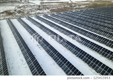 Aerial view of snow melting from covered solar photovoltaic panels at sustainable electric power plant for producing clean electrical energy. Low effectivity of renewable electricity in winter 125413953