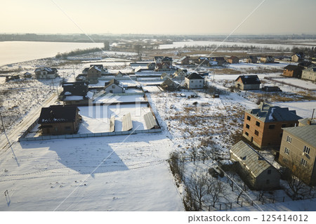Aerial view of private homes with snow covered roofs in rural suburbs town area in cold winter Aerial view of private homes with snow covered roofs in rural suburbs town area in cold winter 125414012