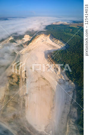 Aerial view of open pit mining of limestone materials for construction industry with excavators and dump trucks. Aerial view of open pit mining of limestone materials for construction industry with excavators and dump trucks. 125414018