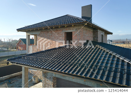 Aerial view of house roof top covered with ceramic shingles. Tiled covering of building under construction Aerial view of house roof top covered with ceramic shingles. Tiled covering of building under construction 125414044