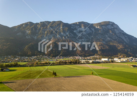 Aerial view of green meadows with villages and forest in austrian Alps mountains. 125414059