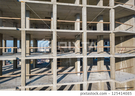 Aerial view of concrete frame of tall apartment building under construction in a city. 125414085