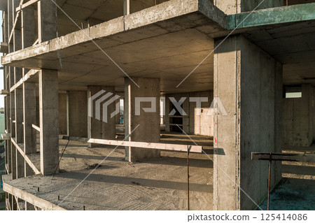 Aerial view of concrete frame of tall apartment building under construction in a city. 125414086