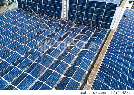 Aerial view of blue photovoltaic solar panels mounted on industrial building roof for producing green ecological electricity. Production of sustainable energy concept. 125414282