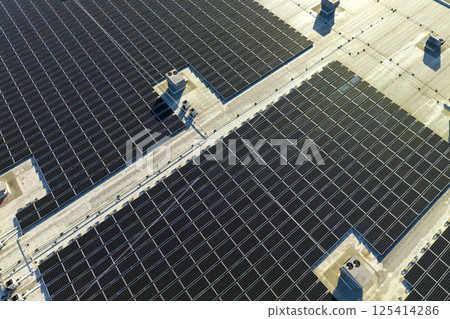 Aerial view of blue photovoltaic solar panels mounted on industrial building roof for producing green ecological electricity. Production of sustainable energy concept 125414286
