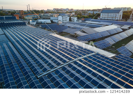 Aerial view of blue photovoltaic solar panels mounted on industrial building roof for producing green ecological electricity. Production of sustainable energy concept Aerial view of blue photovoltaic solar panels mounted on industrial building roof for producing green ecological electricity. Production of sustainable energy concept 125414289