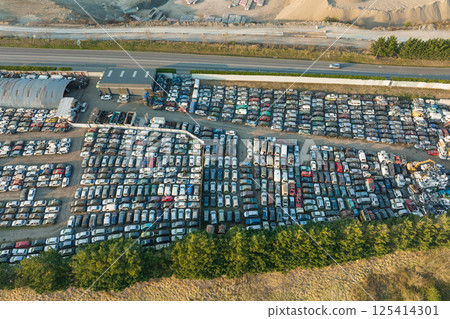Aerial view of big parking lot of junkyard with rows of discarded broken cars. Recycling of old vehicles 125414301