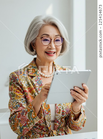 Senior Japanese woman using a tablet (AI generated image) 125414673