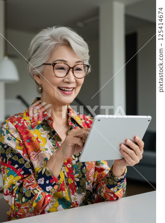 Senior Japanese woman using a tablet (AI generated image) 125414674