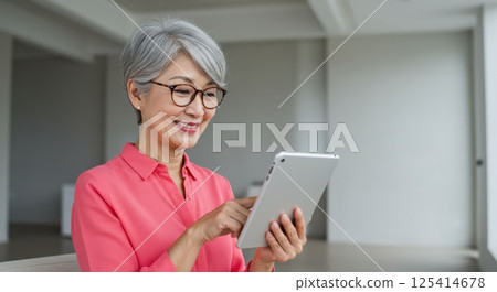 Senior Japanese woman using a tablet (AI generated image) 125414678