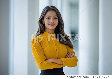 A woman in a yellow shirt and black skirt stands by a window 125414724
