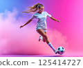 A young woman is kicking a soccer ball on a colorful background 125414727