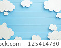 The fluffy clouds appear as paper on a serene blue wooden background 125414730