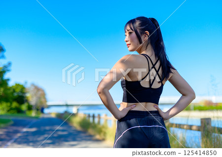 The back view of a cool woman exercising under the blue sky, looking back, diet, exercise, exercise The back view of a cool woman exercising under the blue sky, looking back, diet, exercise, exercise 125414850