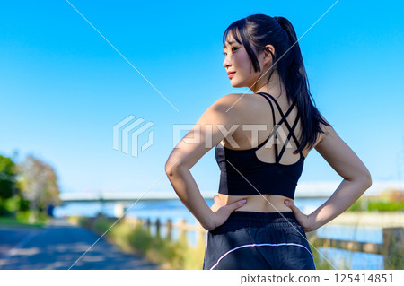 The back view of a cool woman exercising under the blue sky, looking back, diet, exercise, exercise, trimming The back view of a cool woman exercising under the blue sky, looking back, diet, exercise, exercise, trimming 125414851