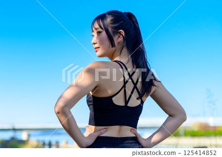 The back view of a cool woman exercising under the blue sky, looking back, diet, exercise, exercise, trimming 125414852