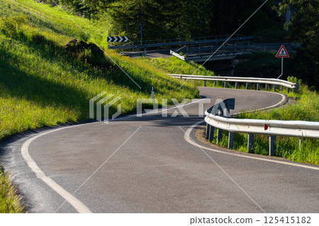 Serene country road with lush greenery and curved pathway near Valley of Funes at Dolomites, Italy Serene country road with lush greenery and curved pathway near Valley of Funes at Dolomites, Italy 125415182