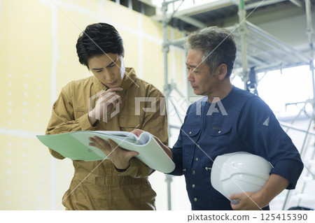 Site supervisors discussing plans at the site 125415390