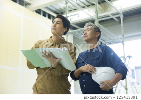 Site supervisors discussing plans at the site 125415391