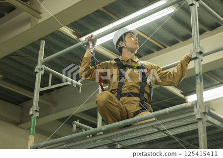 Male worker wearing a full harness 125415411