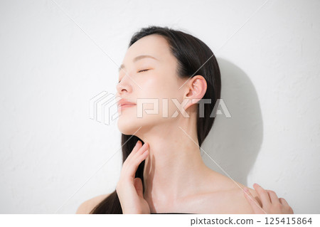 Beauty and beauty image of a black-haired woman taking care of her neck and décolletage around her shoulders 125415864