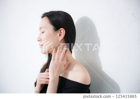 Beauty and beauty image of a black-haired woman taking care of her neck and décolletage around her shoulders 125415865