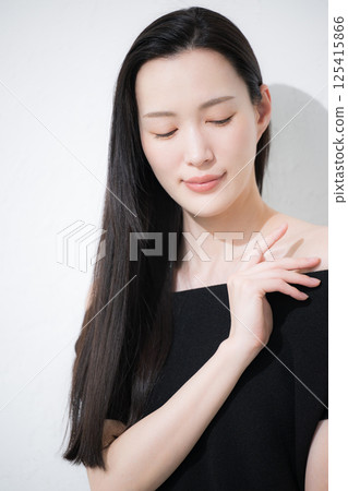 Beauty and beauty image of a black-haired woman taking care of her neck and décolletage around her shoulders Beauty and beauty image of a black-haired woman taking care of her neck and décolletage around her shoulders 125415866