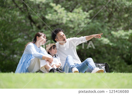 Image of a spring/summer outing holiday with family having a picnic on the grass amidst fresh greenery, pointing at the future and looking towards hope 125416080