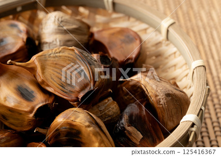 Close-up of black garlic (with skin) in a bamboo basket 125416367