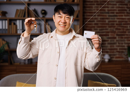 purchase room card, apartment keys, credit card, smiling man, joyful man displays a vial in one hand and an identification card in the other, standing in a welcoming living room filled with books and purchase room card, apartment keys, credit card, smiling man, joyful man displays a vial in one hand and an identification card in the other, standing in a welcoming living room filled with books and 125416969