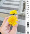 Hand holding a yellow dandelion flower 125417163