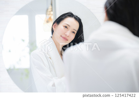 A woman towel-drying her hair after a bath A woman towel-drying her hair after a bath 125417422