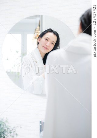 A woman towel-drying her hair after a bath A woman towel-drying her hair after a bath 125417423