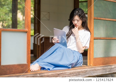 A young woman thinking with a tablet in her hand 125417824
