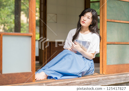 A young woman thinking with a tablet in her hand 125417827